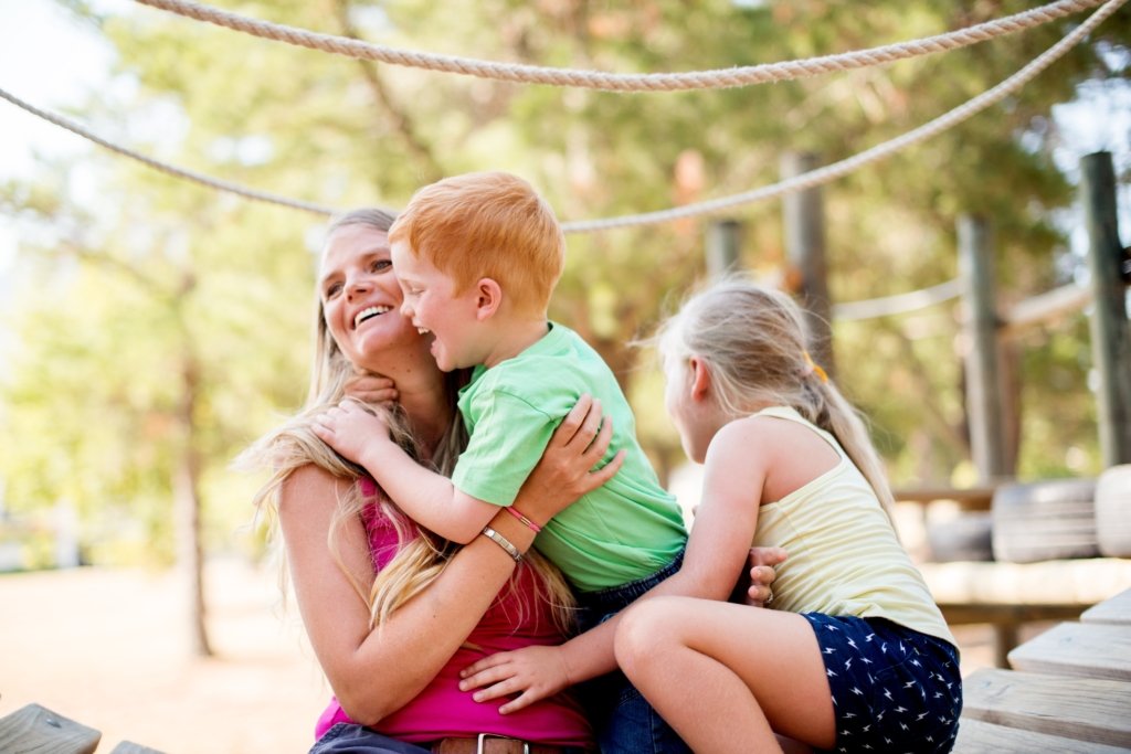 Mother hugging her children while enjoying a peaceful day outdoors after resolving a stressful timeshare situation.